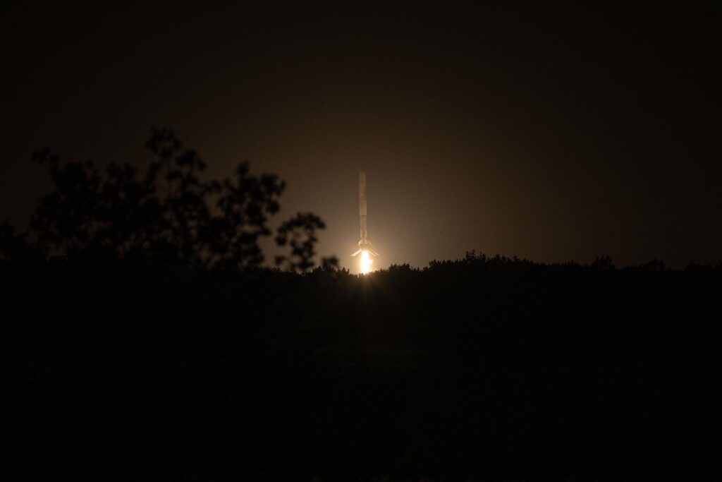 Premier étage de Falcon 9 à la verticale au moment de l'atterrissage, moteur central allumé
