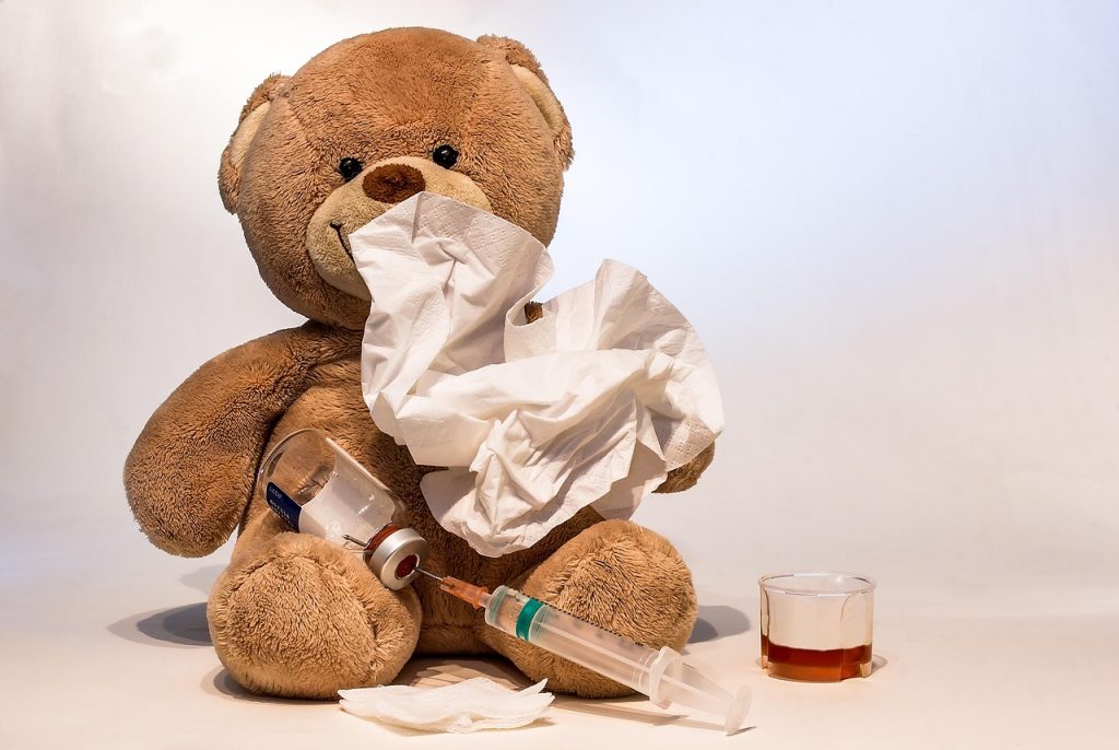 Peluche entourée de mouchoirs et d'un flacon de sirop