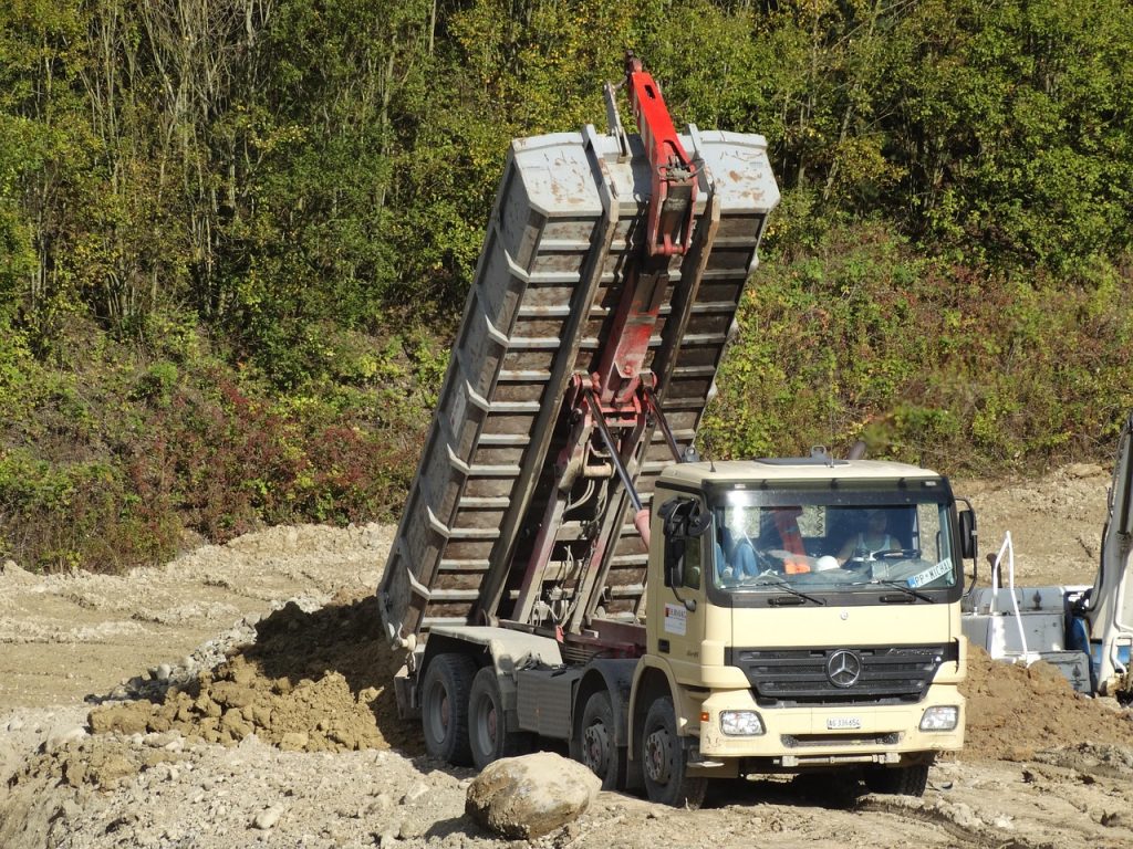 Camion benne livrant de la terre de remblai sur un chantier