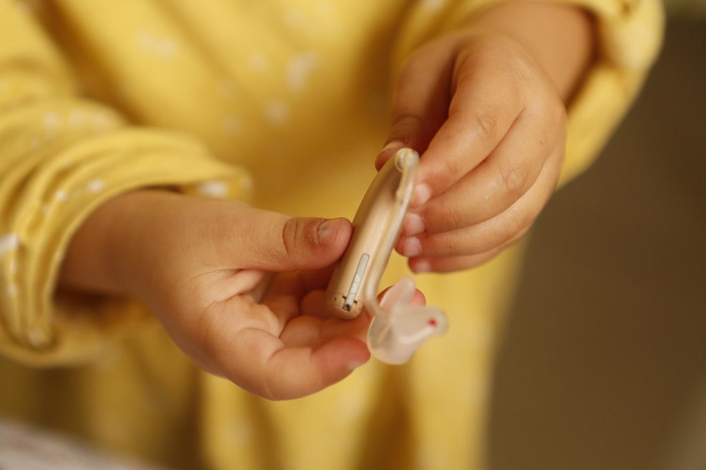 Enfant tenant un appareil auditif