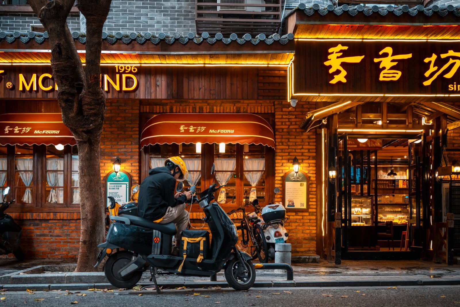 Livreur à scooter dans une rue de ville la nuit